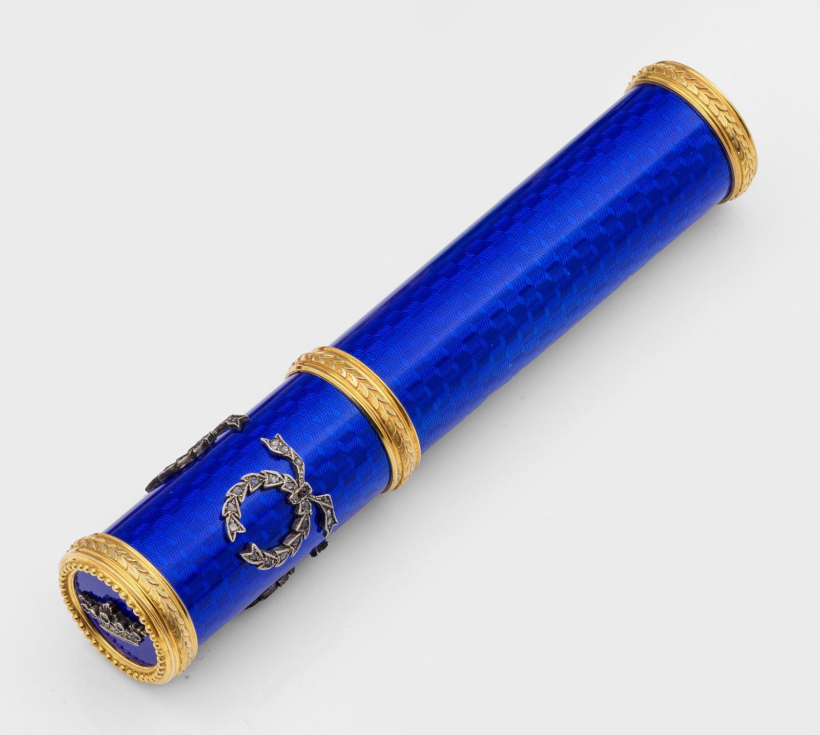 Zigarrenetui: im Stil von Karl Fabergé. Silber vergoldet. Zylindrische Form mit Stulpdeckel. Umlaufend kobaltblau emailliert über feinem, wellenförmig guillochiertem Grund. Auf der Deckelwandung appliziert drei