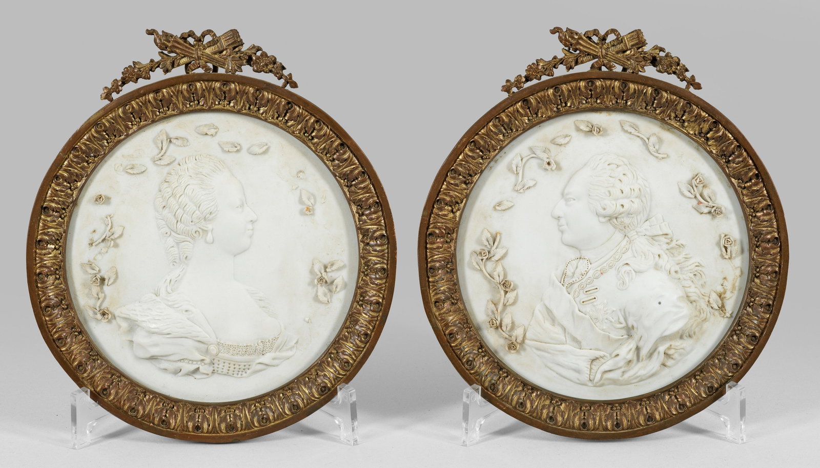 Paar Biskuitporzellan-Reliefs mit Porträtdarstellungen: in vergoldeten Bronzerahmen. Im Hochrelief gearbeitete, blütenbekränzte Tondi mit den Porträts der Kaiserin Maria Theresia bzw. wohl König Ludwig XV. Best./ber.; Eingeritzte Manufakturmarke von S�