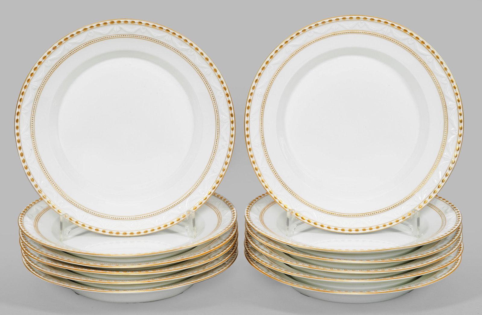 Zwölf Speiseteller mit "Kurland"-Dekor: Auf Fahne umlaufende feine Bordüre mit reliefierten Perlstäben und Tuchgehänge. Goldstaffage. Gold teilw. minim. ber.; Zepter- und Malereimarke. Teller-D. 25 cm. 12 porcelain dinner plates with "Ku