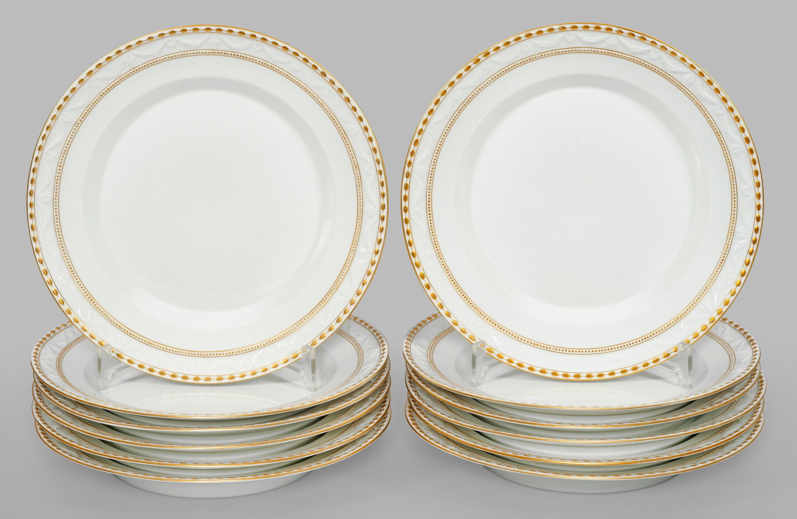 Zwölf Speiseteller mit "Kurland"-Dekor: Auf Fahne umlaufende, feine Bordüre mit reliefierten Perlstäben und Tuchgehänge. Goldstaffage. Gold teilw. minim. ber.; Zepter- und Malereimarke. Teller-D. 25 cm. 12 porcelain dinner plates with "K