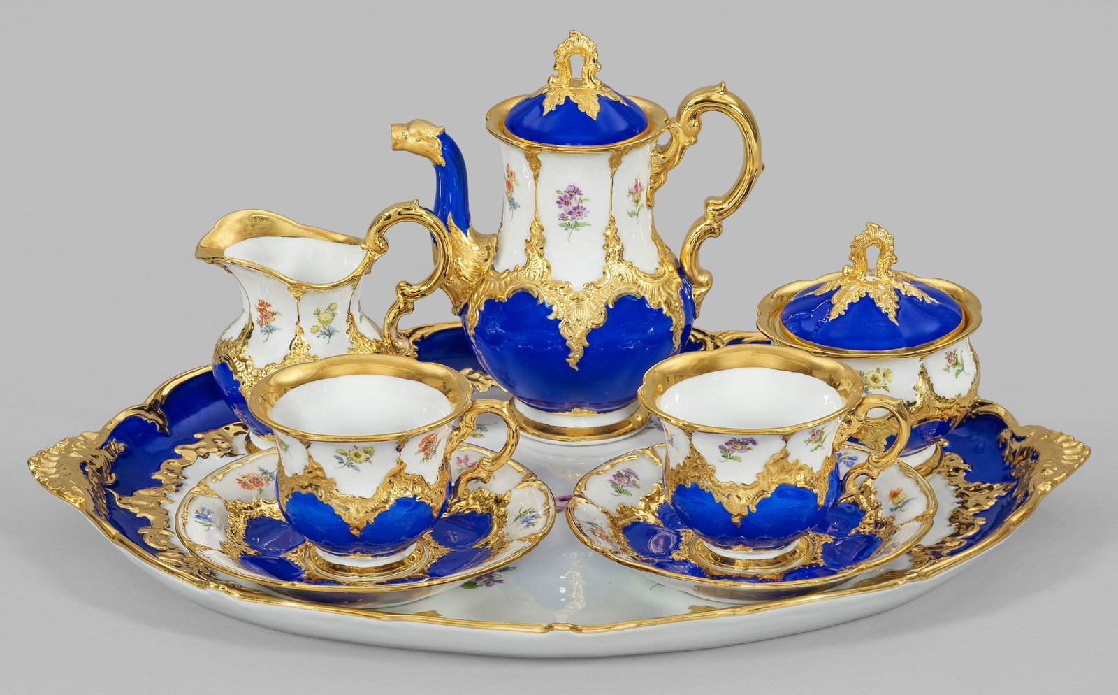 Prächtiges Meissen-Dejeuner "B-Form" mit: blauem Fond für 2 Personen. 6-tlg., Mokkakanne, Sahnegießer, Zuckerdose, 2 Kaffeetassen mit Untertassen, großes Tablett. Blauer Fond mit Rocaillen in Glanzgold bzw. Goldbronze sowie mit feinen Stre