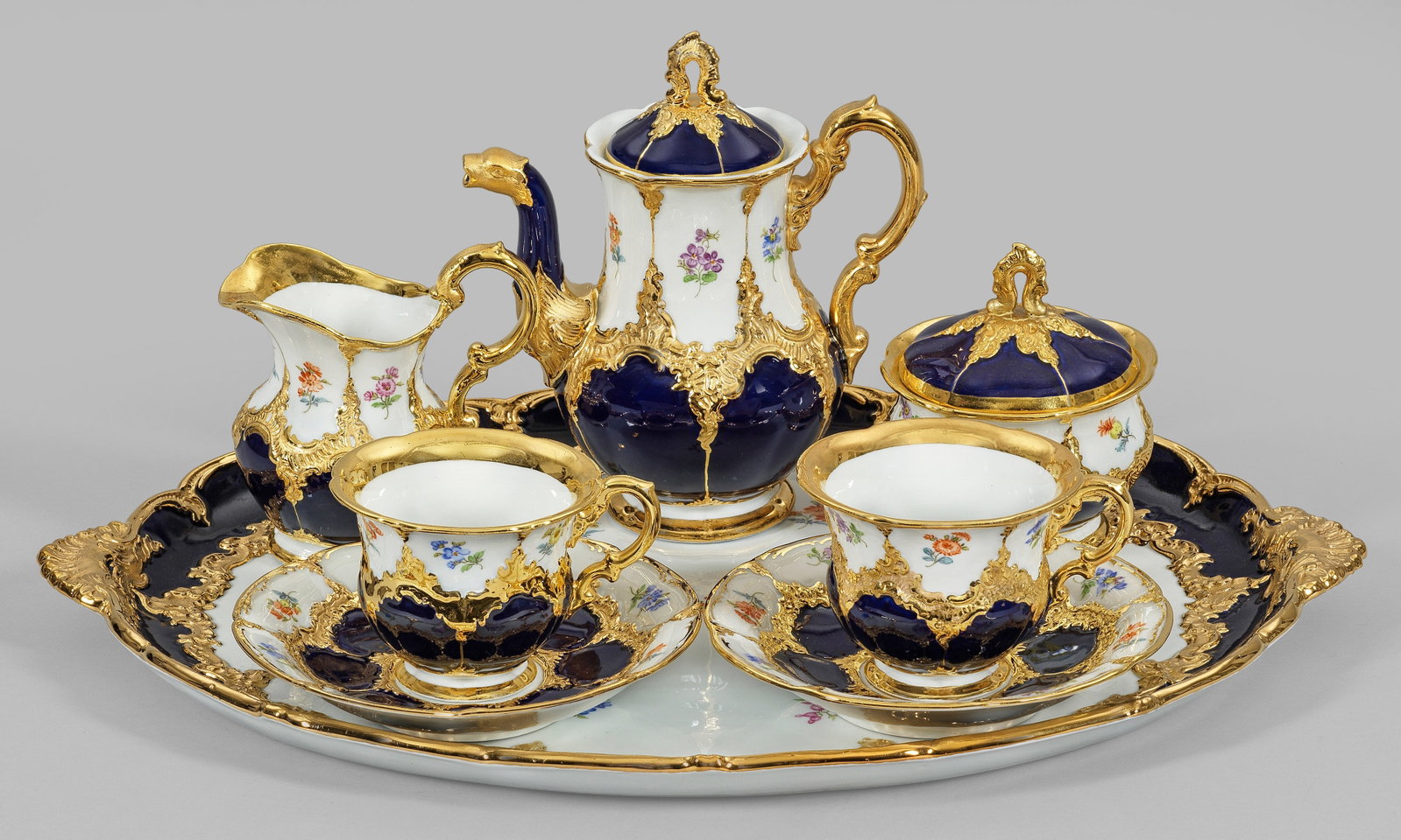 Prächtiges Meissen-Dejeuner "B-Form" mit: kobaltblauem Fond für 2 Personen. 6-tlg., Mokkakanne, Sahnegießer, Zuckerdose, 2 Kaffeetassen mit Untertassen, großes Tablett. Kobaltblauer Fond mit Rocaillen in Glanzgold bzw. Goldbronze sowie mit