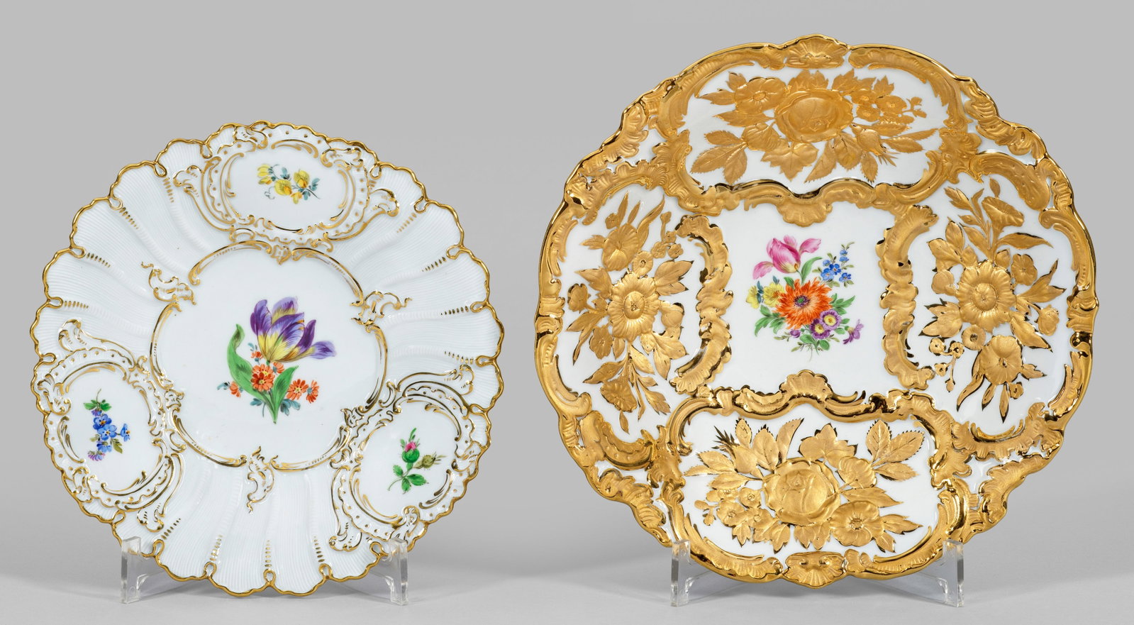 Zwei Prunkschalen: Runde Form mit passig geschweiftem Rand. Auf der Wandung und im vertieften Spiegel Blüten und Streublumen in polychromer Malerei bzw. reiche Rocaille- und Blütenreliefs in Goldstaffage und Goldbronz