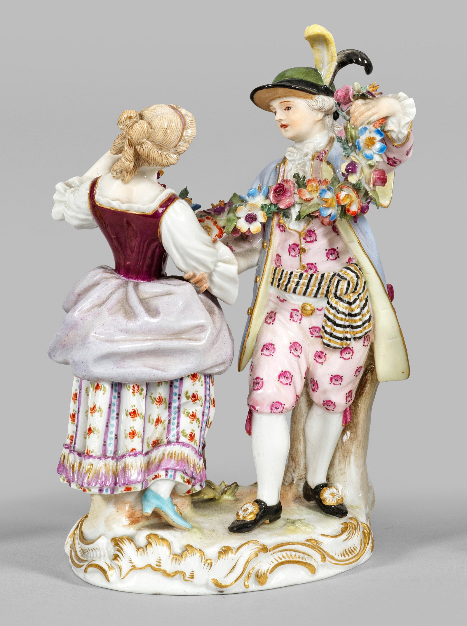 Tanzgruppe: Auf Rocaillesockel stehendes galantes Tanzpaar eine Blütengirlande in den Händen haltend. Polychrome Malerei mit Goldstaffage. Modell-Nr. D 11. Partiell best.; Schwertermarke. H. 16 cm. A porcelain 