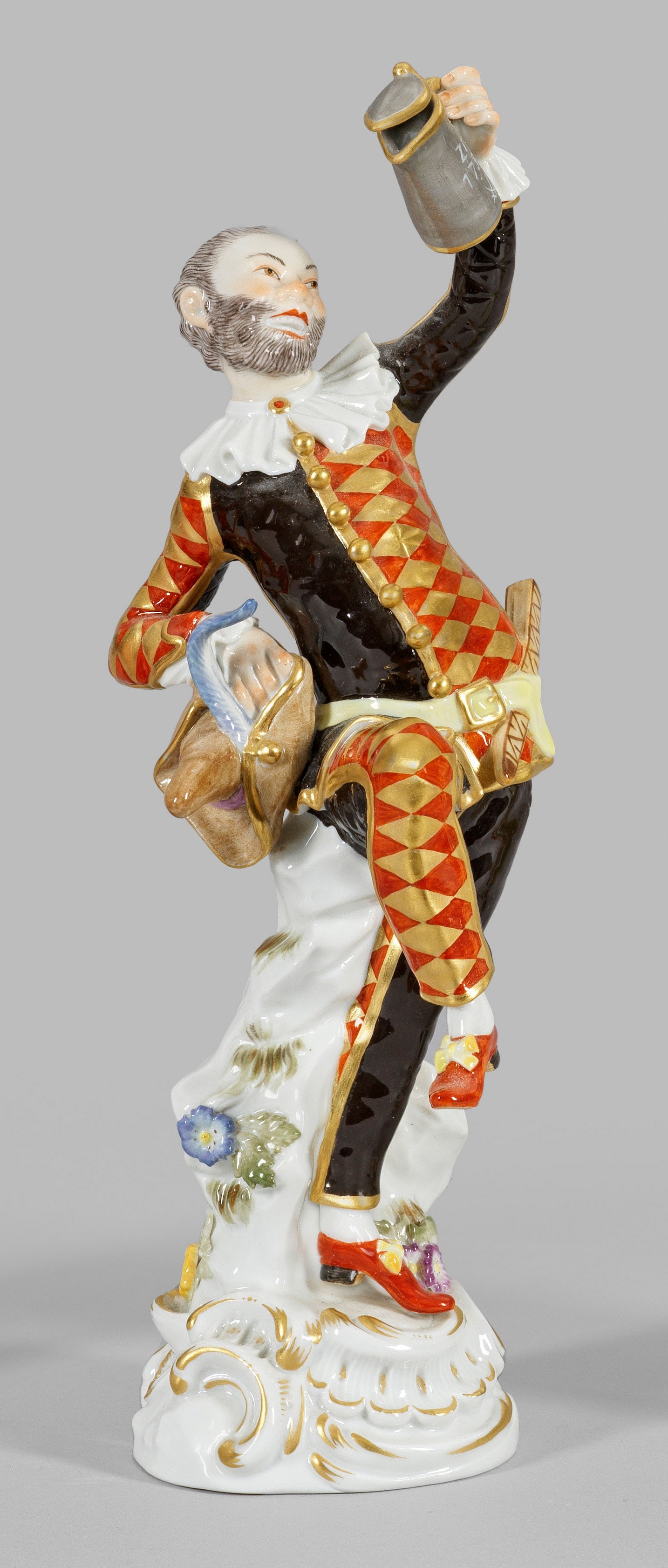 Tanzender Harlekin mit Deckelkanne: aus der Italienischen Kömodie Auf hohem, rocaillereliefiertem Sockel, in Tanzhaltung stehender Hofkomödiant Joseph Ferdinand Müller, gen. Zanni Müller als Harlekin, in kariert-schwarzem Kostüm, i
