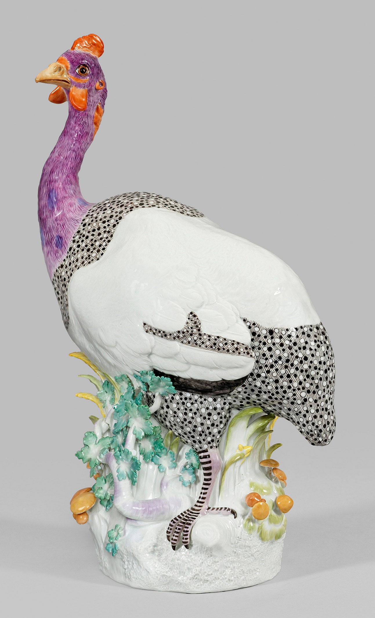 Große Tierfigur eines Perlhuhns von Meissen: Auf ovalem Natursockel zwischen Getreide, Pilzen und Blattwerk stehendes, aufmerksam blickendes Perlhuhn mit fein reliefiertem, farbenprächtigen Gefieder. Polychrome Malerei. Entw. Johann Joachim Kae