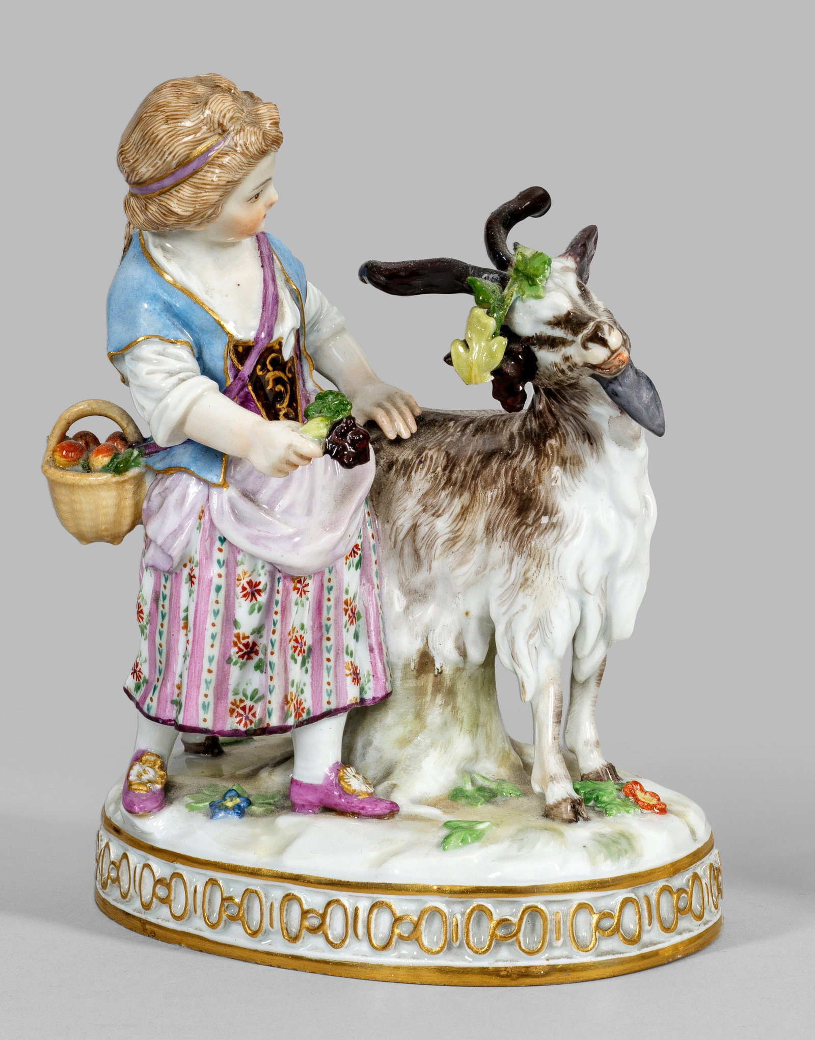 Mädchen mit Ziegenbock: Auf ovalem Terrainsockel mit reliefierter Ornamentbordüre stehendes Gärtnermädchen, einen Ziegenbock mit einer Weinlaubgirlande schmückend. Polychrome Malerei mit Goldstaffage. Entw. Johann Carl S