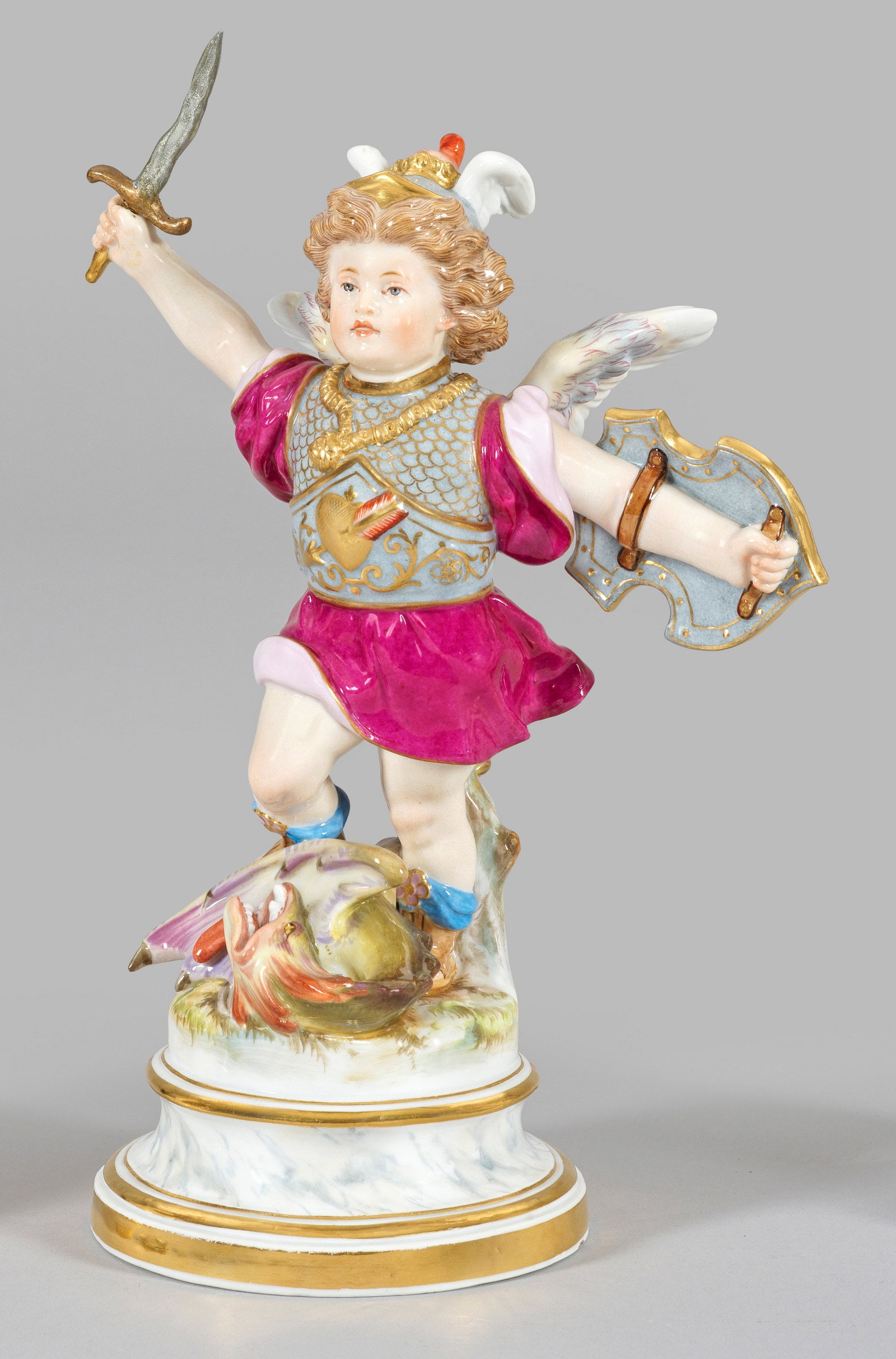 "Amor als Held". Originaltitel: Auf profiliertem, marmoriertem Rundsockel, triumphierend auf dem Leib eines Drachens stehender Amor als Heldengestalt (Drachentöter), ausgestattet mit Harnisch, Flügelhelm und Krone sowie mit Schwer