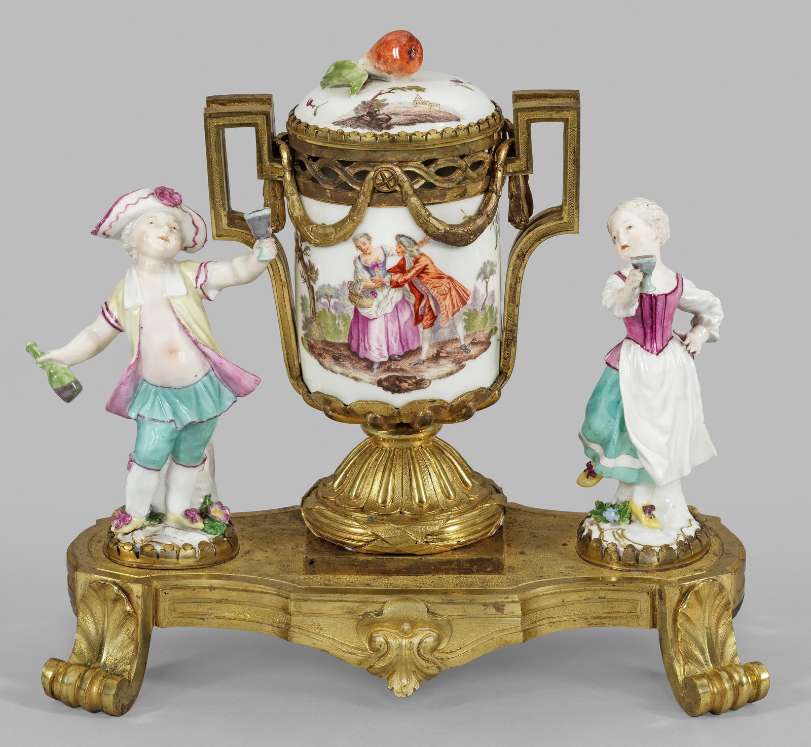 Louis XIV-Brûle Parfum mit Meissener Komödiantenkindern: Porzellan und vergoldete Bronze. Passig geschweifter, von vier Blattvoluten getragener Sockel. Über dem godronnierten Scheibenfuß mit Kreuzbändern seitlich aufsteigende Henkel à la grecque mit wel