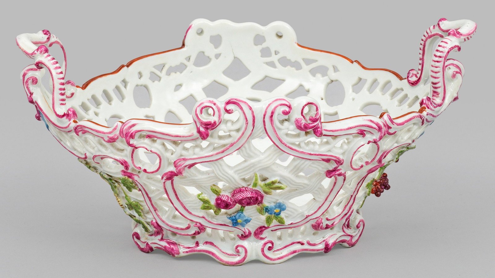 Zierkorb mit Blütendekor: Oval aufgewölbter Korpus mit durchbrochen gearbeiteter Wandung. Rocaillegerahmte Blumen- und schleifenbekrönte Früchteranken. Polychrome Malerei mit Purpurstaffage. Minim. rest.; Brandrisse. Schwer