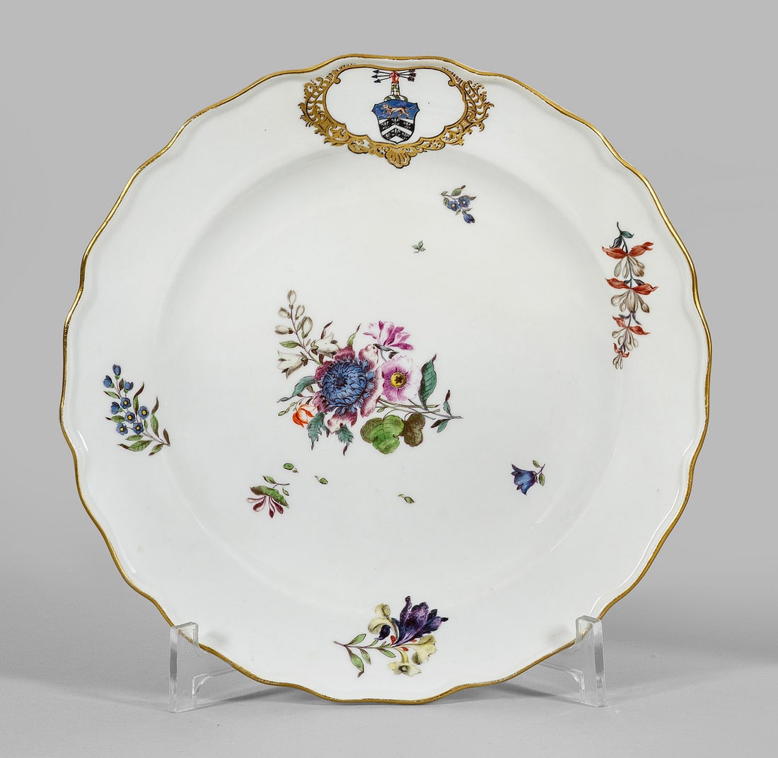 Teller aus dem Service des Konsul Joseph Smith: Runde, leicht vertiefte Form mit passig geschweiftem Rand. Zentral auf der Fahne in goldgerahmter Kartusche das Smith-Wappen. Im Spiegel und auf der Fahne Blumengebinde und gestreute Blumen. Polychrom
