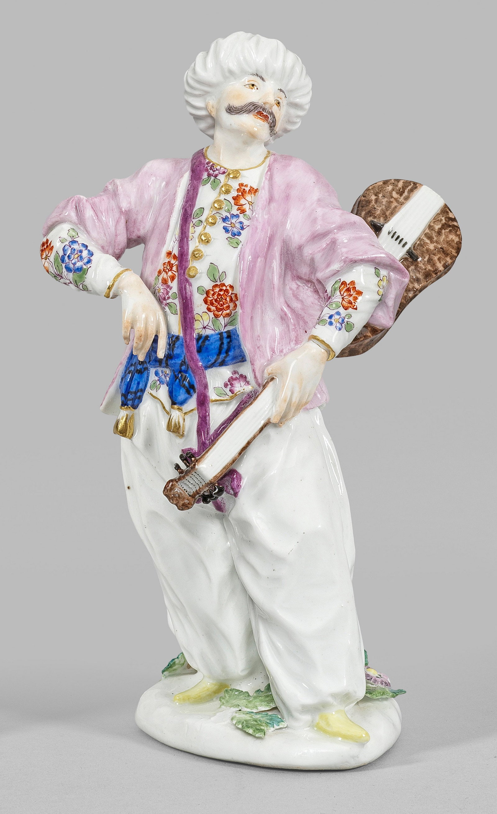 Türke mit Gitarre: Auf einem mit plastischen Blüten und Blättern belegtem Ovalsockel stehender Orientale, eine Gitarre haltend. Polychrome Malerei mit dezenter Goldstaffage. Entw. Peter Reinicke und Johann Friedrich E