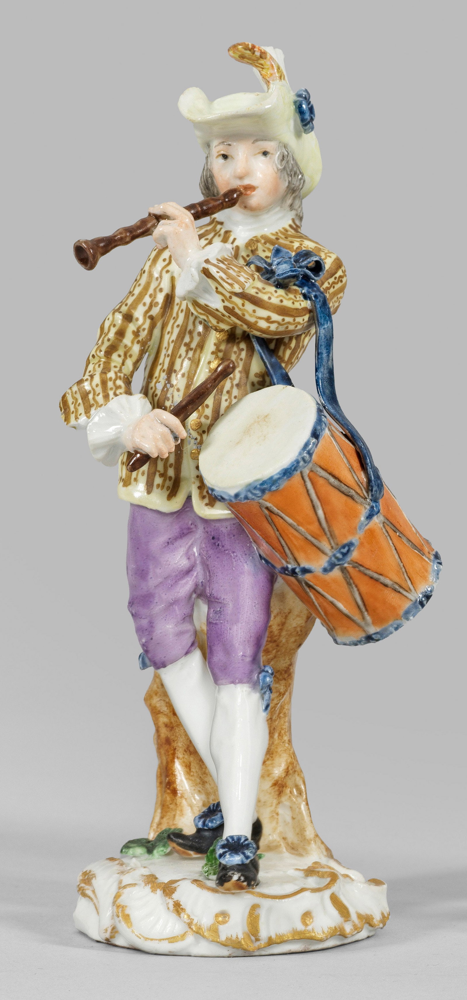 Trommler aus der Serie "Cris de Paris": Vor einem Baumstamm stehender Herr mit Trommel, seine Flöte spielend. Polychrome Malerei mit Goldstaffage. Entw. Johann Joachim Kaendler und Peter Reinicke nach Stichen von Christoph Huet, um 1753/54