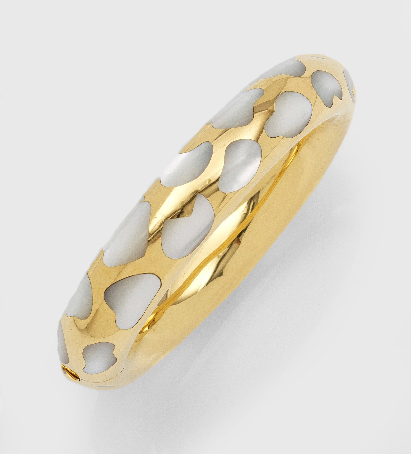 Armreif von Tiffany & Co, Angela Cummings: aus den 1980er Jahren Gelbgold, gest. 750. Bombierter Reif, schauseitig organischer Intarsien-Dekor aus Perlmutt. Herstellerzeichen. Gew. ca. 76,45 g. Angela Cummings gilt als eine der bedeutendsten S