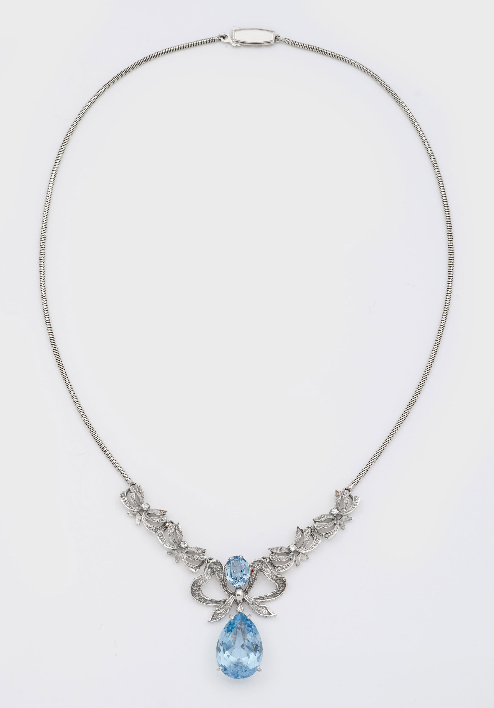 Topas-Collier aus den 1940er Jahren: Weißgold, 14 ct.; Floral gestaltetes Mittelstück mit 2 Skyblue-Topasen von zus. ca. 10 ct., akzentuiert durch 8/8 Diamanten, an feiner Schlangenhautkette. Gew. ca. 22,72 g. Necklace set with 2 sky b
