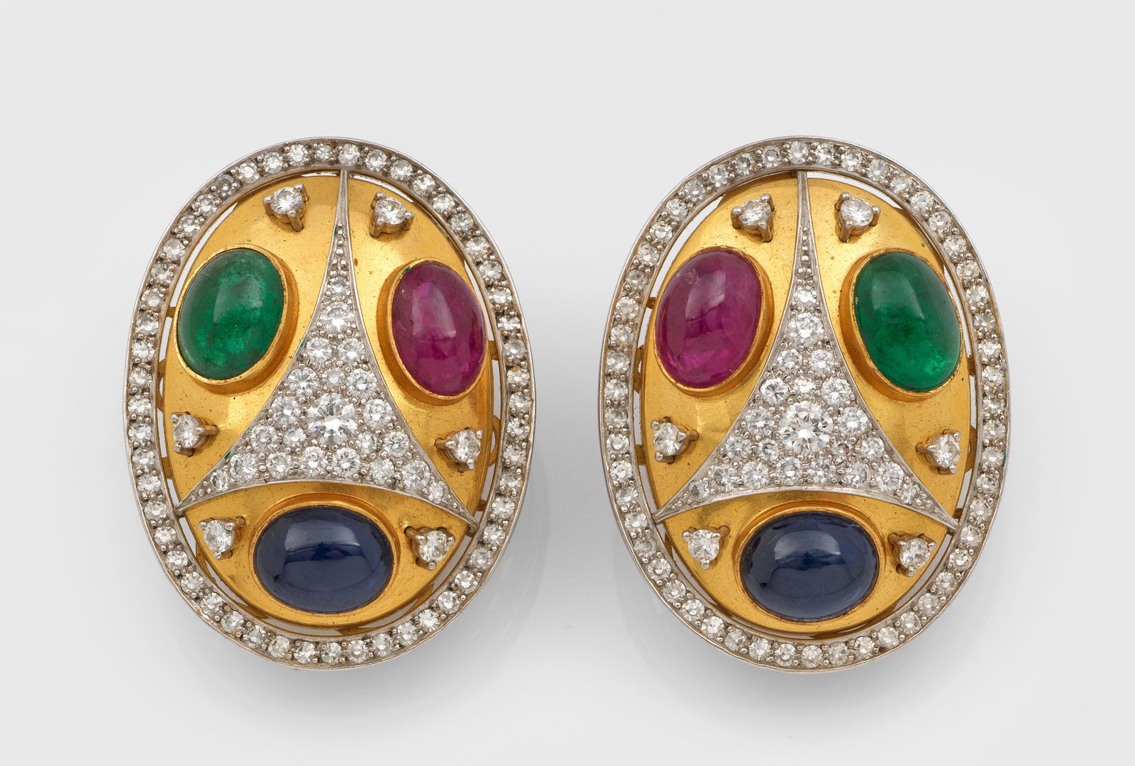 Paar extravagante Multicolor-Ohrclips von Roesner, Hamburg: Gelbgold, gest. 750. Schauseitig besetzt mit Rubinen, Saphiren und Smaragden von zus. ca. 22,08 ct. im Cabochonschliff, akzentuiert durch Brillanten von zus. ca. 3,07 ct. (F-G/if-vvs). Ges.-Gew. ca. 4