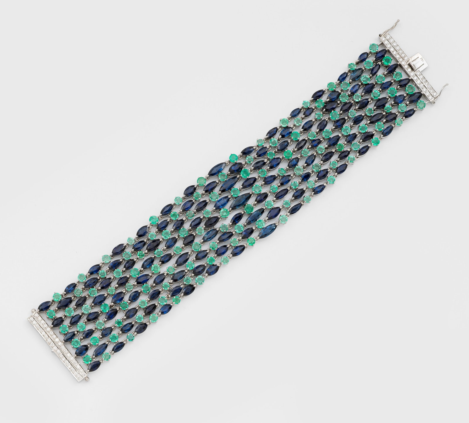 Mondänes Manschettenarmband mit Saphiren und Smaragden: Weißgold, gest. 750. Gitterartig ausgefaßt mit nahezu kornblumenblauen Saphiren von ca. 41,49 ct. im Wechsel mit leuchtendgrünen Smaragden von ca. 16,45 ct., akzentuiert durch Diamanten von zus. ca