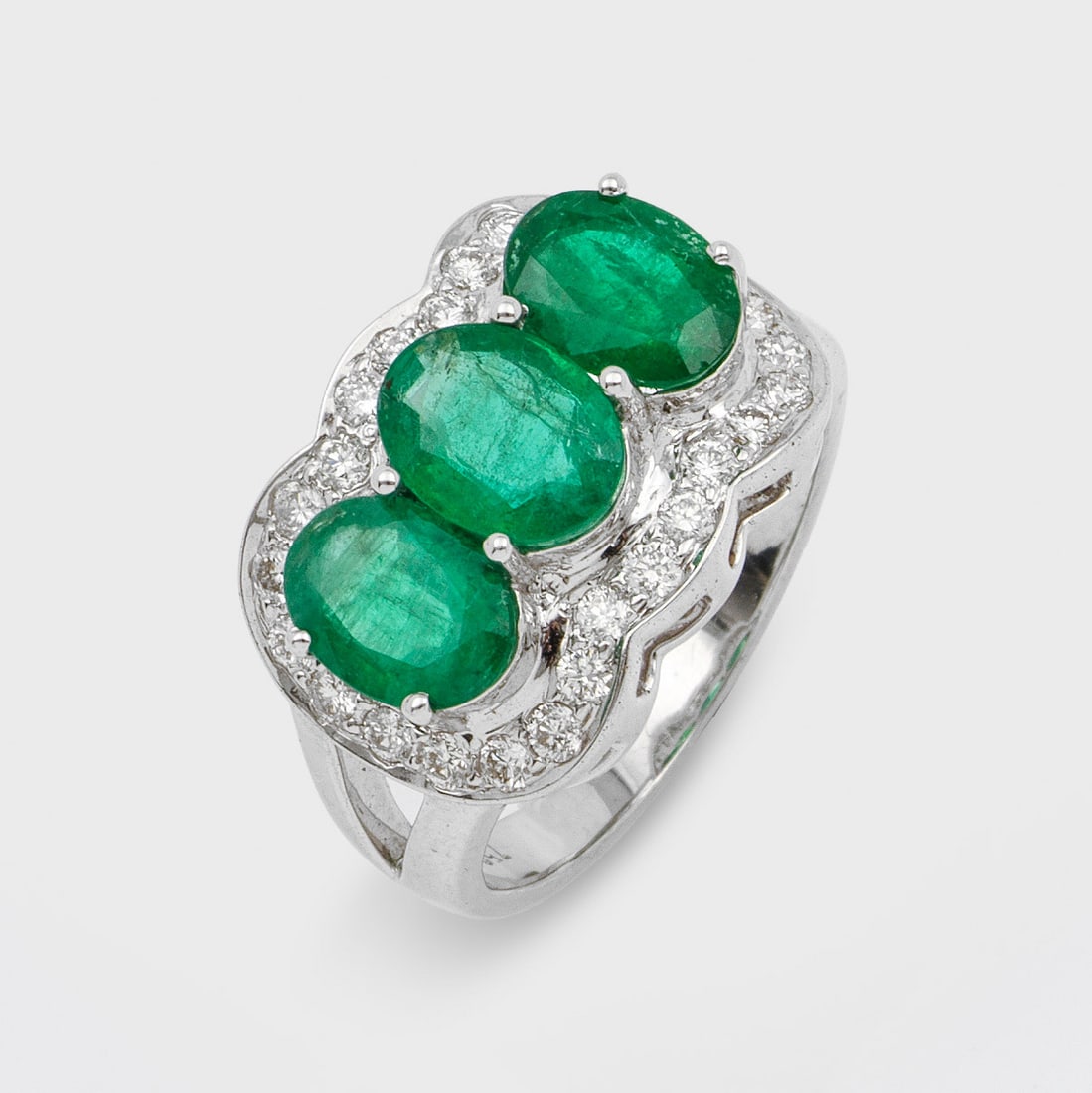Klassischer Smaragd-Diamant Ring: Weißgold, gest. 750. Zentral angeordnet 3 Smaragde von zus. ca. 3,11 ct., weich umkränzt von Brillanten zus. ca. 0,60 ct.; Gew.ca. 8,64 g. Ring set with 3 emeralds approx. 3,11 ct. and diamonds appr