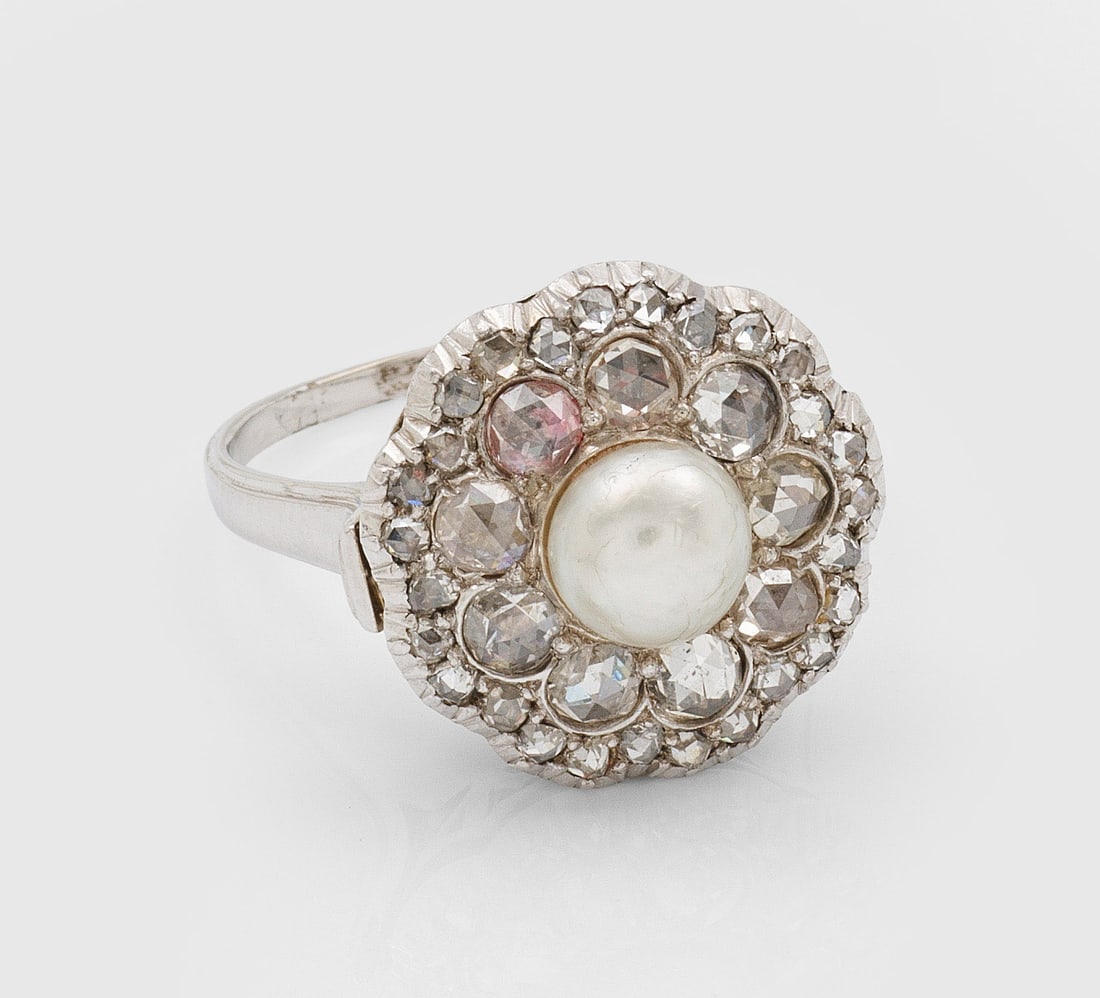 Belle Epoque-Diamantring mit Perle: Weißgold, gest. 585. Zentral besetzt mit cremefarbener Perle von ca. 6,6 mm in Boutonform, entouriert von Diamantrosen von zus. ca. 1,00 ct.; Gew. ca. 9,96 g. Ring set with a pearl approx. 6,6 mm and