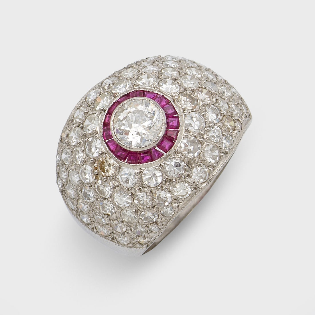 Art Déco Rubin-Diamantring: Weißgold. 18 ct.; Zentral besetzt mit einem Altschliffdiamanten von ca. 0,70 ct., entouriert von taubenblutroten Rubincarrées sowie korrespondierenden kleinen Diamanten von zus. ca. 2,00 ct.; Gew. c