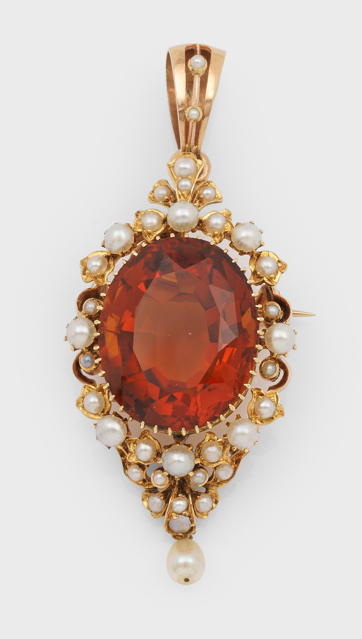 Belle Epoque Citrin-Anhänger: Gelbgold, 14 ct.; Medaillonförmiger Anhänger zentral besetzt mit einem orange-gelben Citrin von ca. 20 mm x 14 mm, entouriert von kleinen Saatperlen. Gew. ca. 12,19 g. Auch als Brosche tragbar. Pend