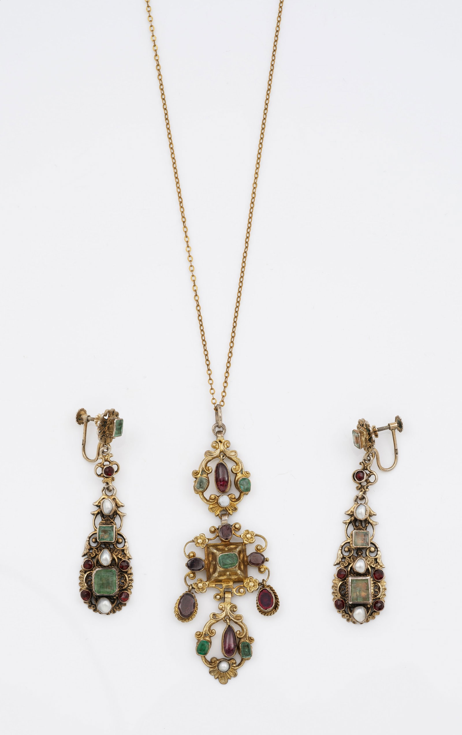 Belle Epoque-Demi Parure aus Siebenbürgen, um 1880: Silber und Gold, 9 ct.; Chandelierförmiger Anhänger aus Voluten und Blütenrosetten, schauseitig besetzt mit weißen Halb-Flussperlen und folierten, farbigen Steinen, an feiner Gliederkette. Korresp