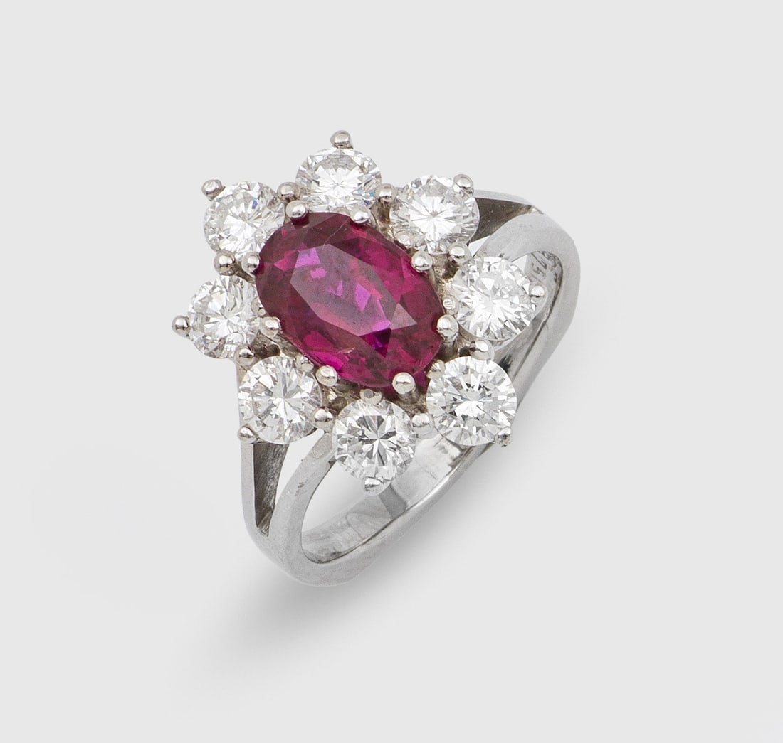 Klassischer Brillant-Entouragering mit Rubin: Weißgold, gest. 750. Zentral besetzt mit einem taubenblutroten Rubin von ca. 1,00 ct., entouriert von Brillanten von zus. ca. 1,20 ct.; Gew. ca. 6,09 g. Ring set with a pigeon blood red ruby approx. 