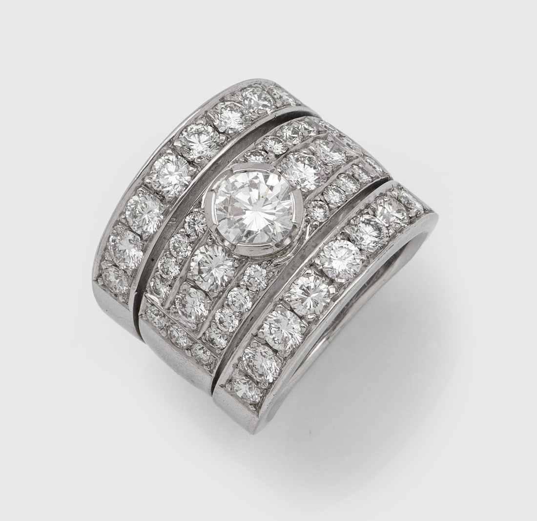 Glamouröser Brillant-Bandring: Weißgold, gest. 585/750. Dreireihige Bandschiene im leichten Verlauf, zentral besetzt mit einem Brillantsolitär von ca. 1,00 ct. (J/vvs-vs), umrahmt von korrespondierenden Brillanten von zus. ca. 2,