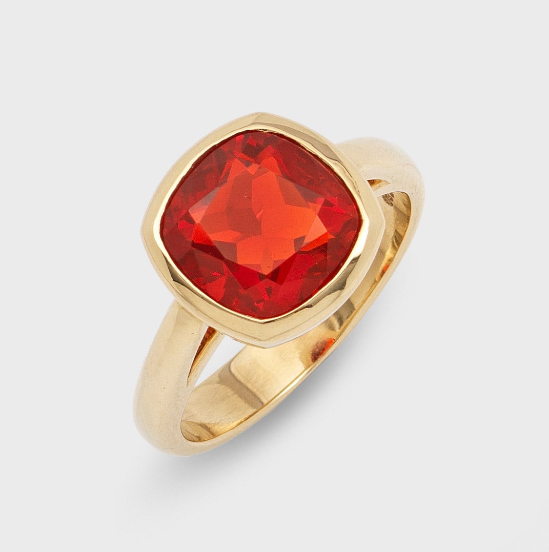 Klassischer Feueropal-Ring: Gelbgold, 18 ct.; Zentral besetzt mit einem orange-rotem Feueropal von ca. 3,00 ct., in korrespondierender Zargenfassung. Gew. ca. 9,49 g. Ring set with an orange red fire opal approx. 3,00 ct., in 18