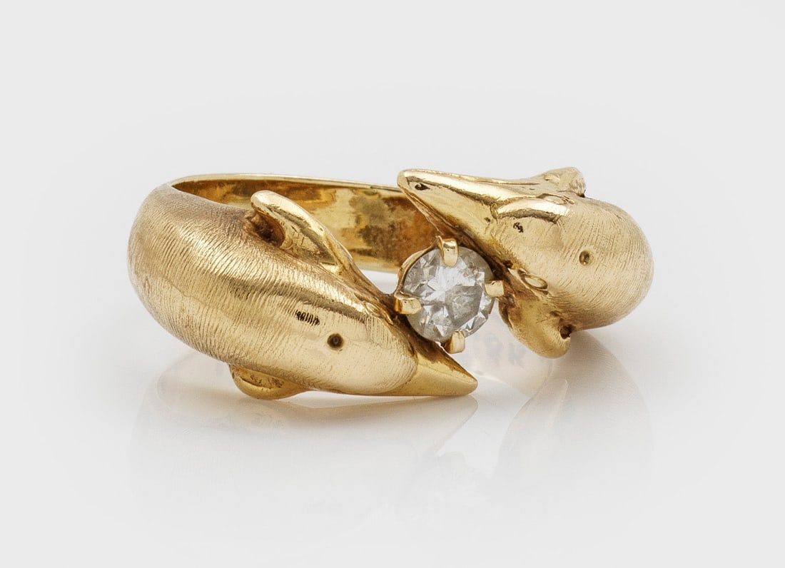 Delphin-Ring mit Brillanten: Gelbgold, gest. 18 ct.; Diagonal verlaufende Ringschiene in Delfinenköpfen endend mit zentral eingesetztem Brillantsolitär von ca. 0,20 ct.; Gew. ca. 10,88 g. Dolphin ring set with a diamond