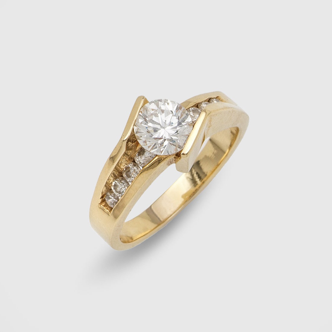 Moderner Brillantsolitär-Ring: Gelbgold, gest. 14 ct.; Diagonal verlaufende Ringschiene, mit zentralem Brillantsolitär von ca. 1,20 ct. (I-J/vs), flankiert von kleinen Brillanten von zus. ca. 0,20 ct.; Gew. ca. 6,39 g. Ring set wi
