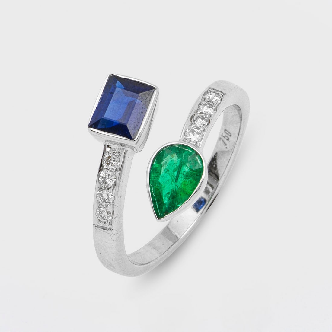 Moi & Toi Saphir-Smaragdring: Weißgold, gest. 750. Diagonal verlaufende Ringschiene besetzt mit einem Smaragdtropfen von ca. 0,54 ct und einem Saphirbaguette von ca. 0,85 ct., akzentuiert durch Brillanten von ca. 0,17 ct.; Gew. c