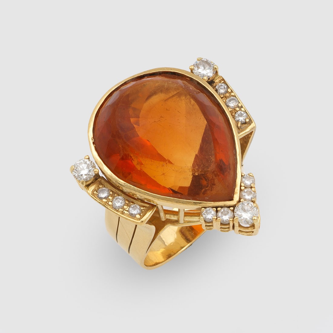 Pompöser Madeira-Citrinring von Roesner, Hamburg: Gelbgold, gest. 750. Zentral besetzt mit einem orangegelbem Citrin von ca. 40 ct. im Pendeloque-Schliff, akzentuiert durch Brillanten von zus. ca. 0,95 ct. (G/if-vsi). Sehr feine Ateliersarbeit. Gew. 