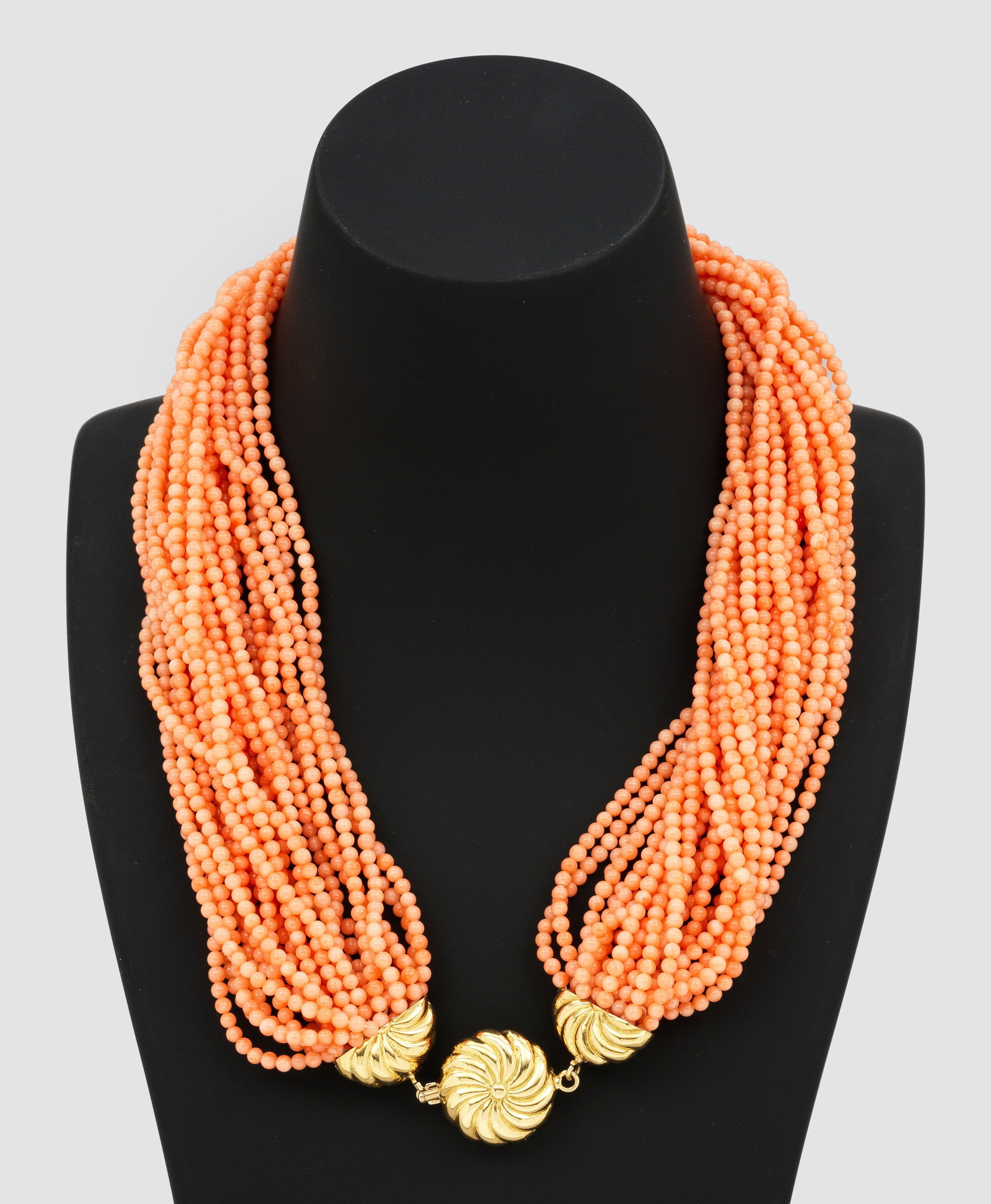 Dekoratives Korallen-Collier: Gelbgold, gest. 750. 25-reihig aus lachsfarbenen Korallen-Perlen von ca. 2 mm, fein ziselierte Goldschliesse. Ges.-Gew. ca. 89,07 g. Necklace set with coral pearls, in 18 k gold.