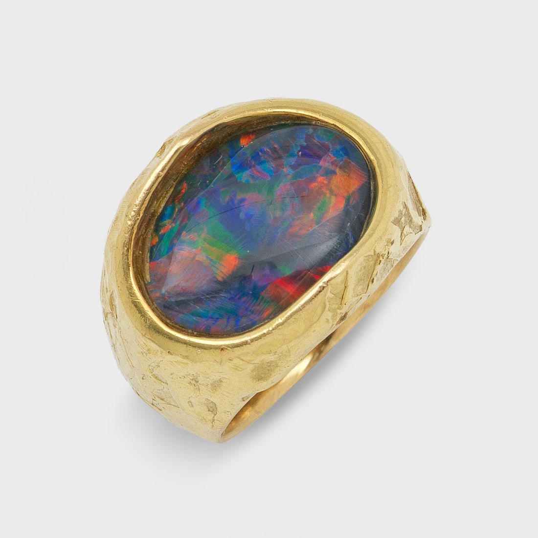 Moderner Boulder-Opalring: Gelbgold, gest. 750. Massive, gehämmerte, strukturierte Ringschiene, zentral besetzt mit einer Opal-Triplette. Gew. ca. 23,00 g. Ring set with an opal triplette, in 18 k gold.