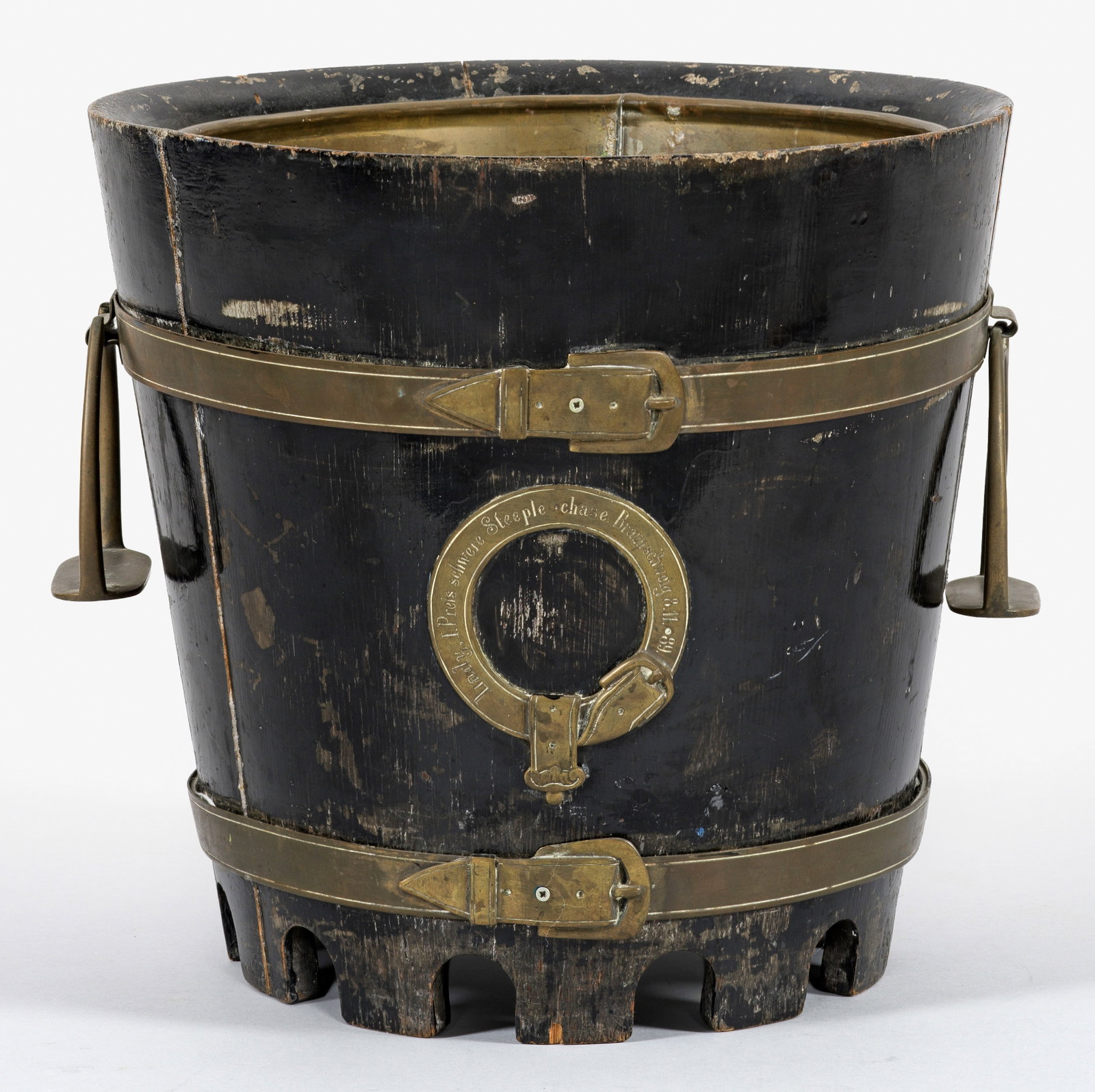 Weinkühler als Siegestrophähe des Braunschweiger: "Steeple chase" 1889 Holz, Schwarz gefasst und Messing. Oben und unten offener konisch leicht ansteigender Korpus. Passiger Messingeinsatz. Umlaufende Messinggürtel mit Schließe und seitlichen Steig