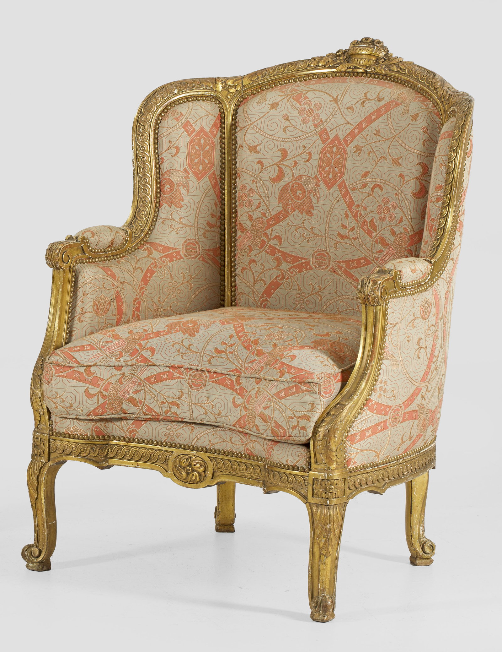 Napoleon III-Bergère: Holz, geschnitzt, gefasst und vergoldet. Schmale, bombierte Zarge mit Wellenbandfries auf Volutenbeinen. Gebogte Stützen für schmale Armlehnen, in gewölbte Rückenlehnenrahmung übergehend. Allseit