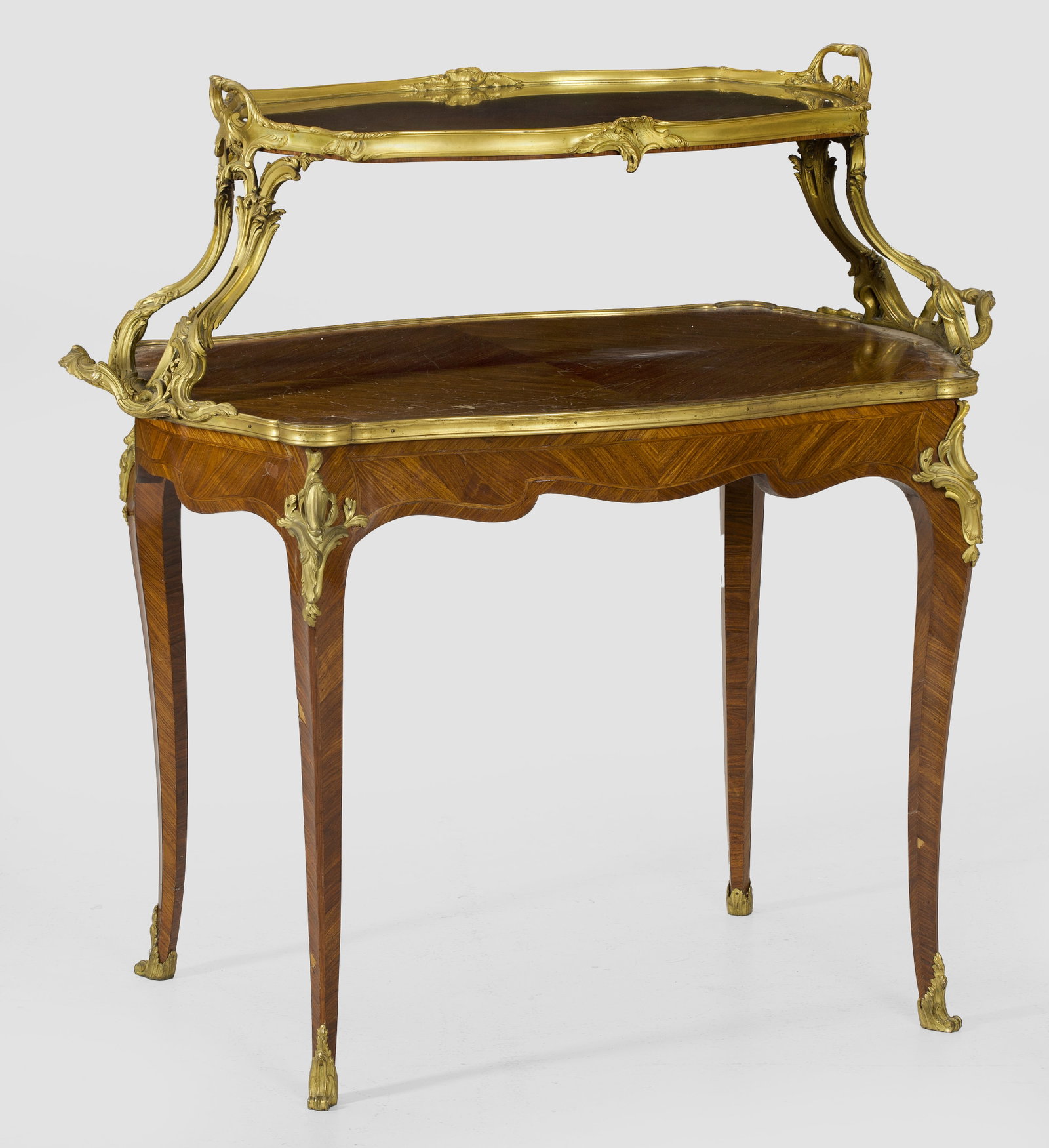 Belle Epoque-Etagèrentisch: Palisander, furniert sowie Applikationen aus Bronze. Passig geschweifte Zarge auf hohen, geschwungenen Beinen. Gering überstehende, profilgerahmte Deckplatte mit seitlichen Handhaben. Davon ausgehend