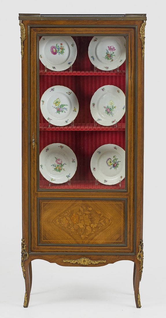 Napoleon III-Salonvitrine: Palisander furniert sowie florale Einlagen aus unterschiedlichen Hölzern. Gerader, hochrechteckiger, dreiseitig verglaster Korpus, flankiert von schmalen, schräggestellten Ecklisenen auf geschweifte
