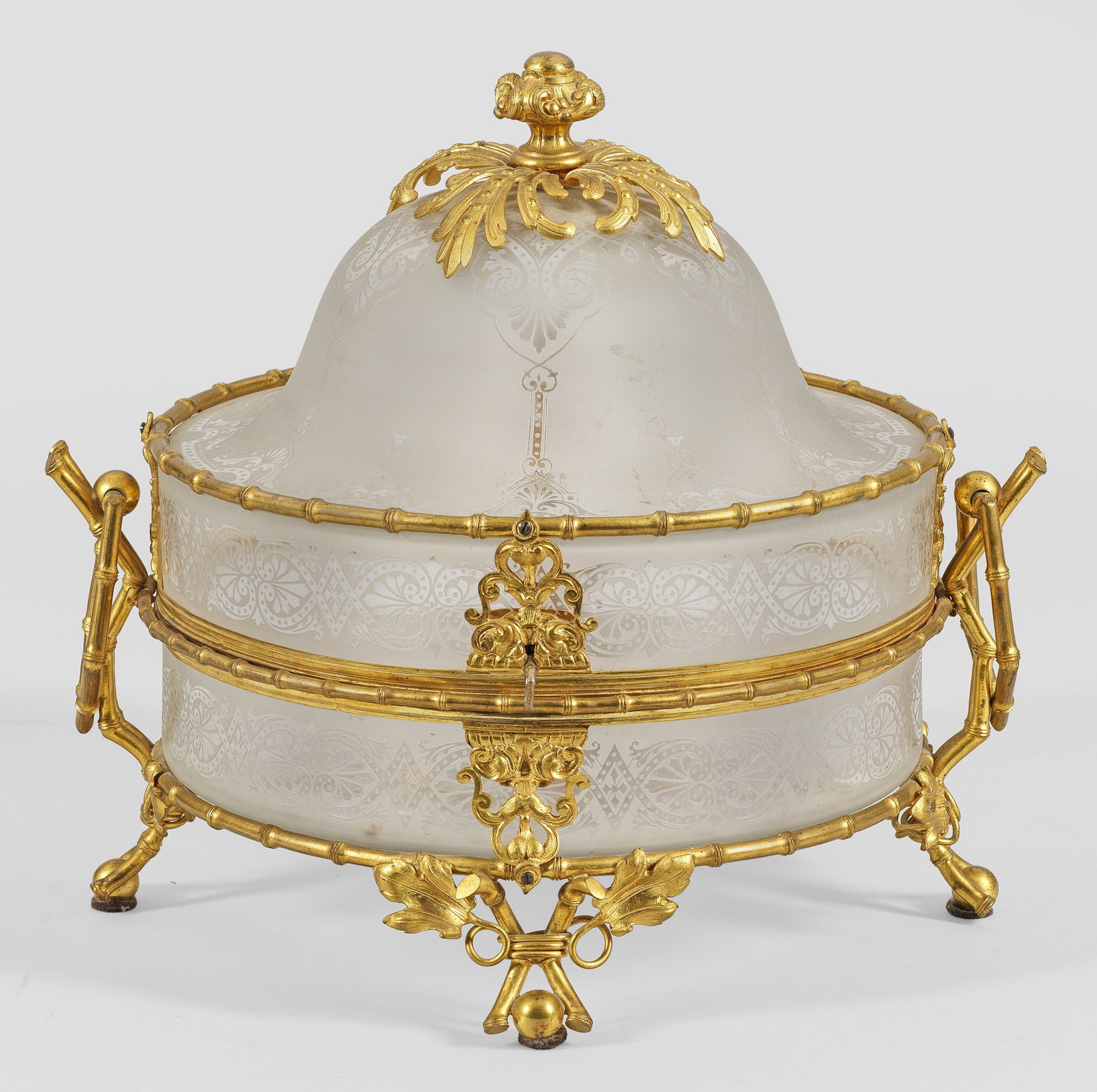 Napoleon III-Likör-Tantalus: Glas und vergoldetes Metall. Walzenförmiger Korpus mit scharniertem Haubendeckel. Von Bambusfüßen getragen und von entsprechenden Bändern konturiet. Matter Fond mit Ornamenten. Florale Bekrönung 
