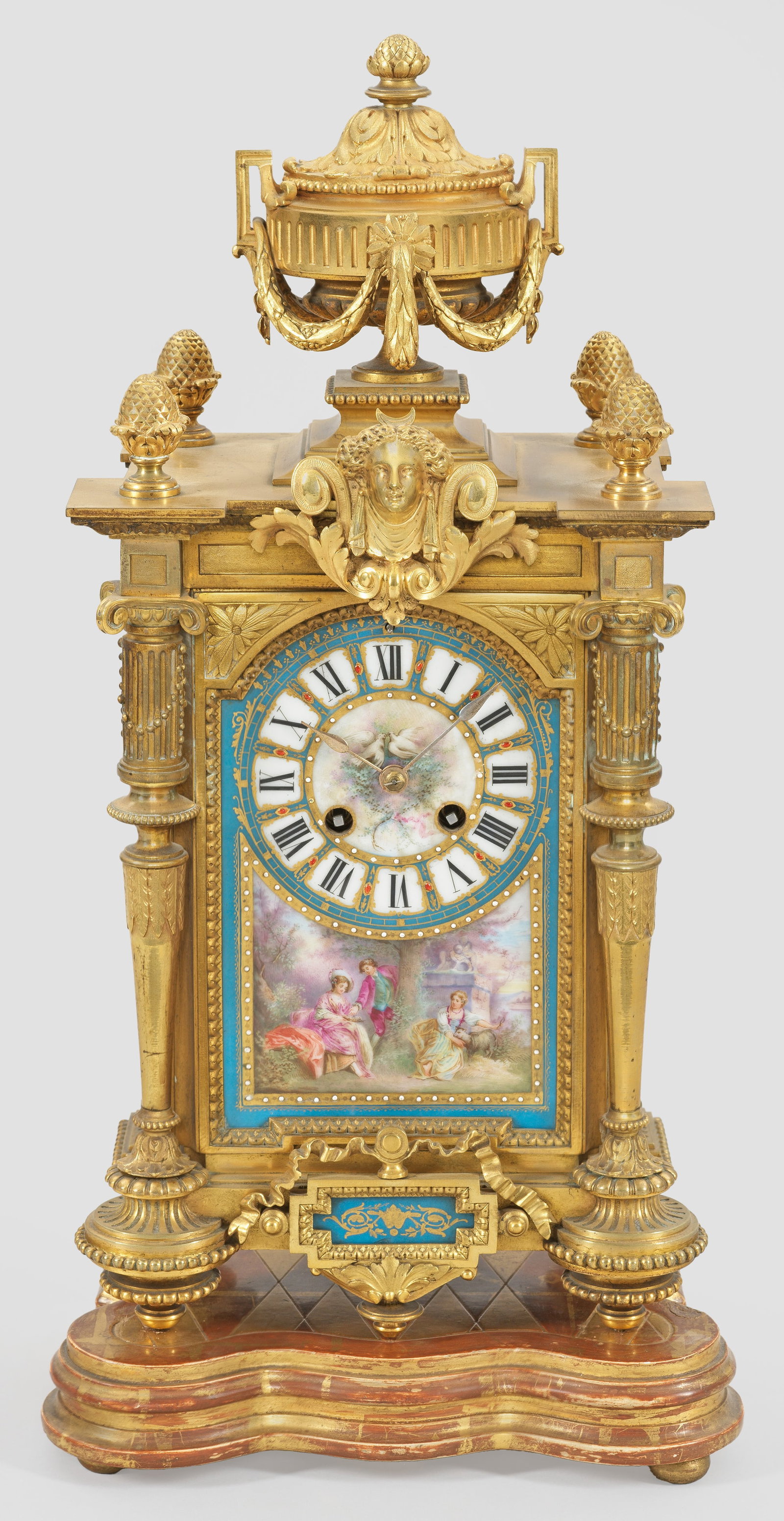 Napoleon III-Pendule: Bronze, vergoldet sowie polychrom gestaltete Porzellanplaketten. Hochrechteckiges Uhrengehäuse, flankiert von eingestellten Balustersäulen mit Pinienknäufen und großer Vasenbekrönung. Reserven mi