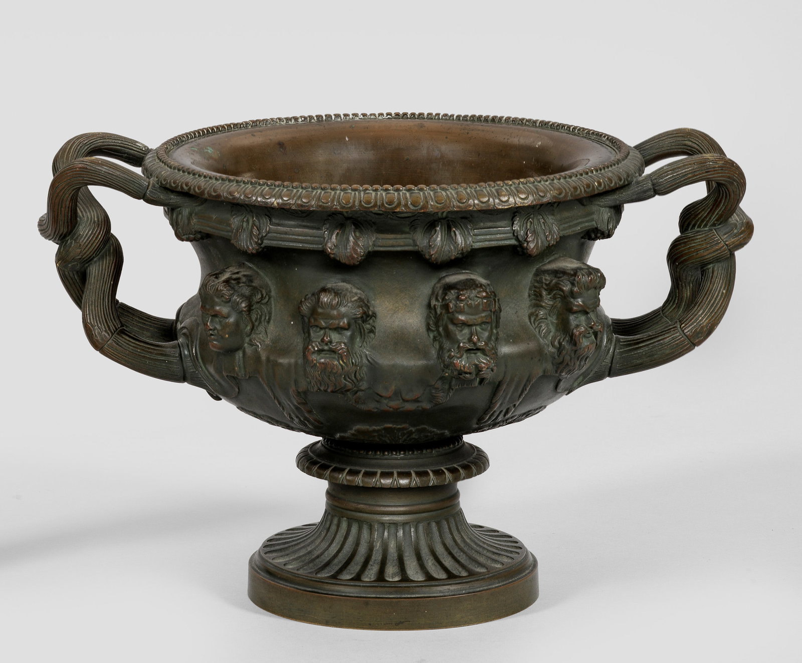 Warwick-Vase als Grand Tour-Objekt: Bronze, dunkel patiniert. Über gestuft ansteigendem Profilsockel balusterförmiger, teilw. kannelierter Korpus nach dem Vorbild der berühmten 1771 wieder entdeckten Warwick-Vase aus dem 2. Jh., seit