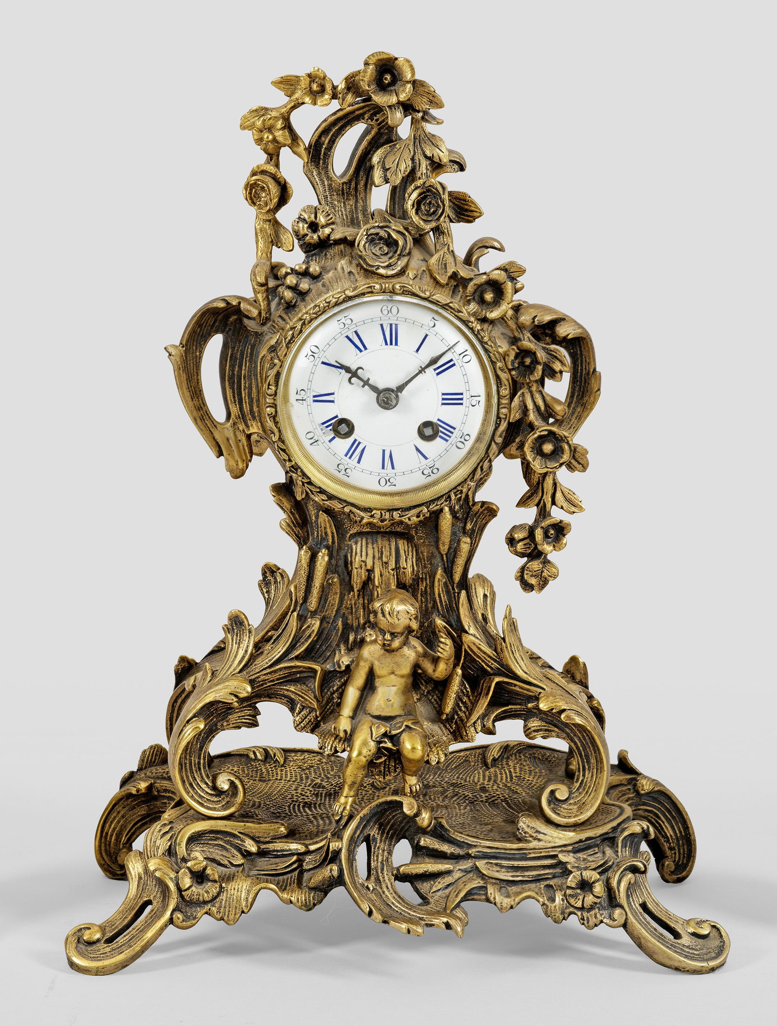Pendule im Rokoko-Stil: Bronze. Über üppigem Rocaillesockel balusterförmiger Korpus aus Blattvoluten als Träger für rundes Uhrengehäuse mit asymmetrisch angelegter Rocaillebekrönung. Verglastes Zifferblatt. Pendulenwe