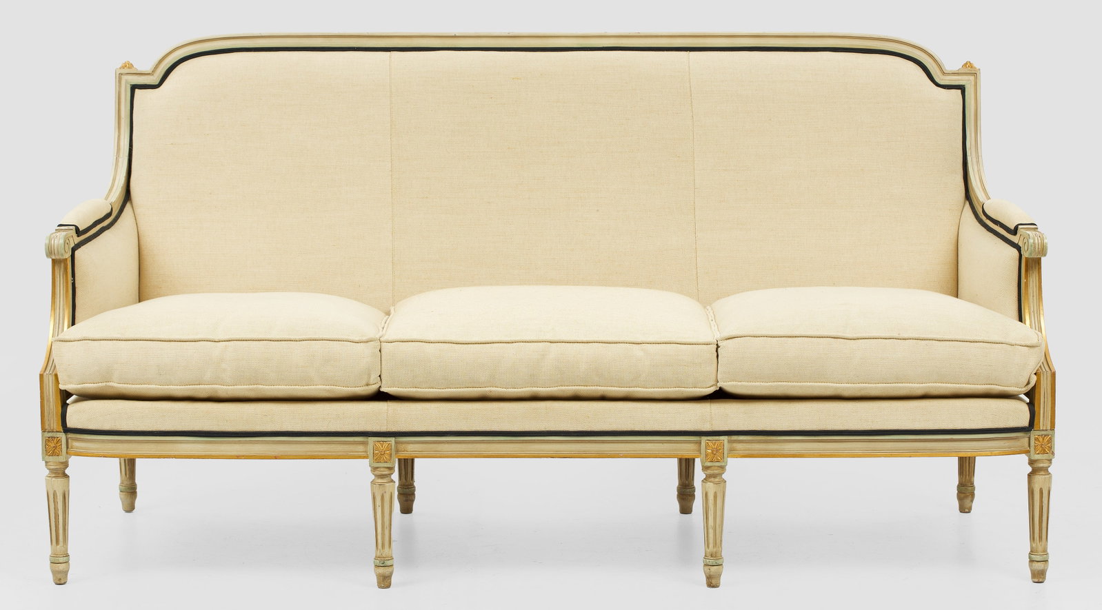 Sofa im Louis XVI-Stil: Holz, cremefarben gefasst und teilw. vergoldet. Gerade Zarge auf schlanken, kannelierten Balusterbeinen. Gebogte Stützen für schmale, geschweift ansteigende Armlehnen. Profilierte, leicht gewölbte 