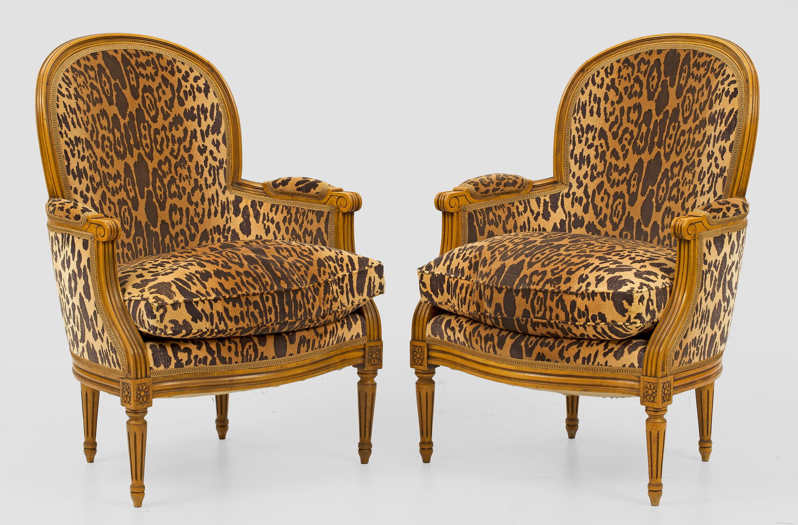 Paar Louis XVI-Begrèren: Buchenholz. Bombierte, profilierte Zarge auf kannelierten Balusterbeinen. Gebogte Stützen für schmale Armlehnen sowie korrespondierende, gewölbte Rückenlehnenrahmung. Allseitig gepolstert und in L