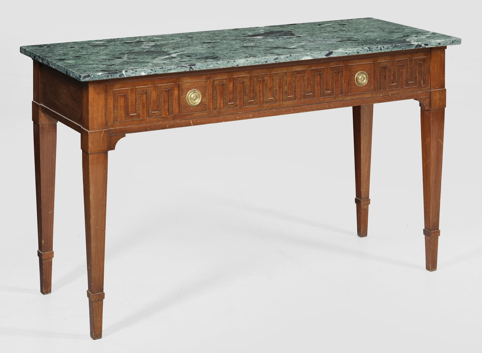 Konsoltisch im Louis XVI-Stil: Mahagoni, furniert. Gerader, einschübiger Zargenkasten auf konischen Vierkantbeinen. In der Front erhabener Dekor aus stilisierten Mäandern. Gering überstehende, rechteckige Deckplatte aus grün ge