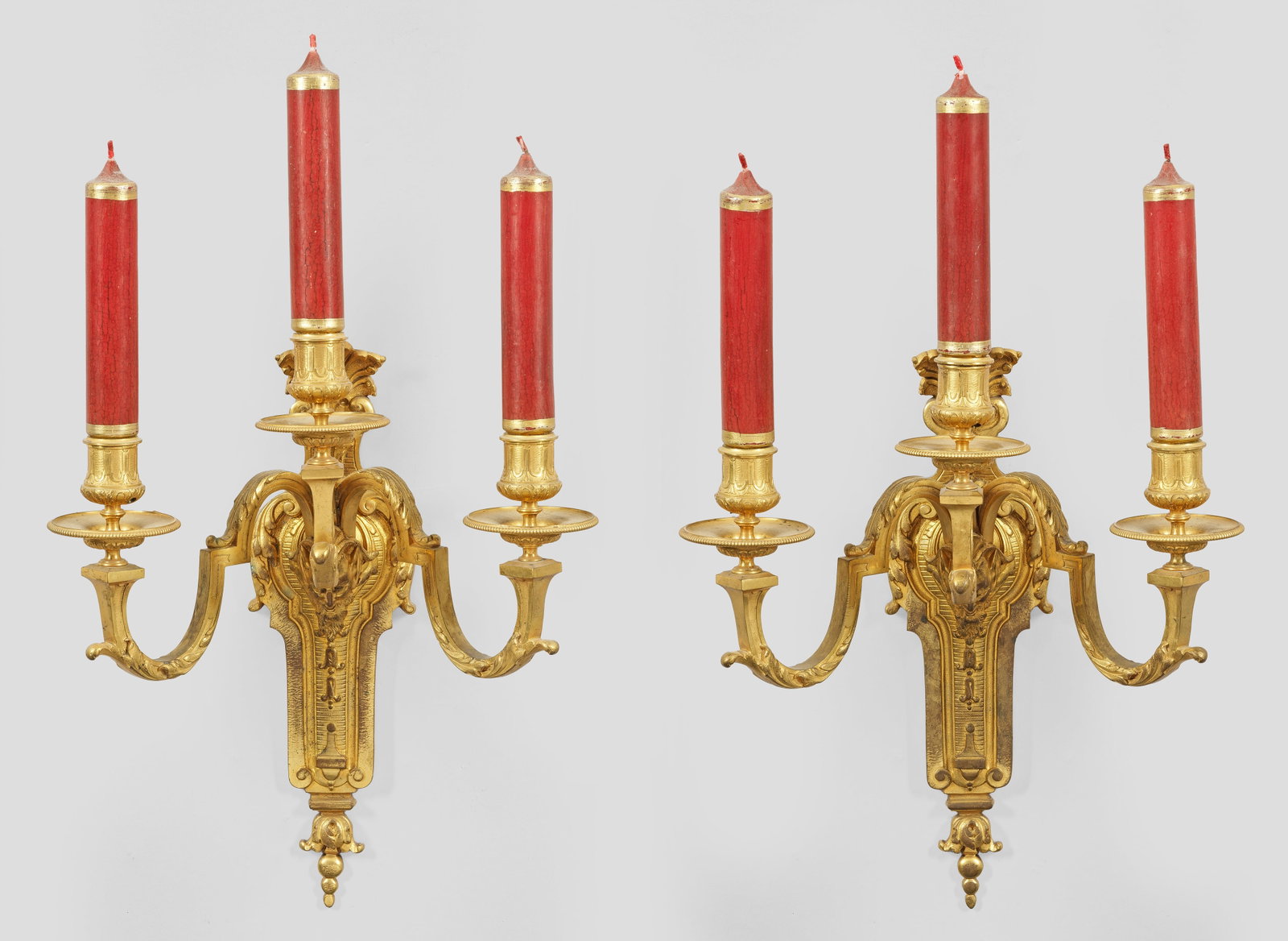 Paar Napoleon III-Wandgirandolen: 3-flg.; Bronze, vergoldet. Flaches, balusterförmiges Wandschild mit Fächerbekrönung. In der Mitte davon ausgehend reliefplastisch gestalteter Faunkopf sowie stark geschwungene, gekantete Leuchterar