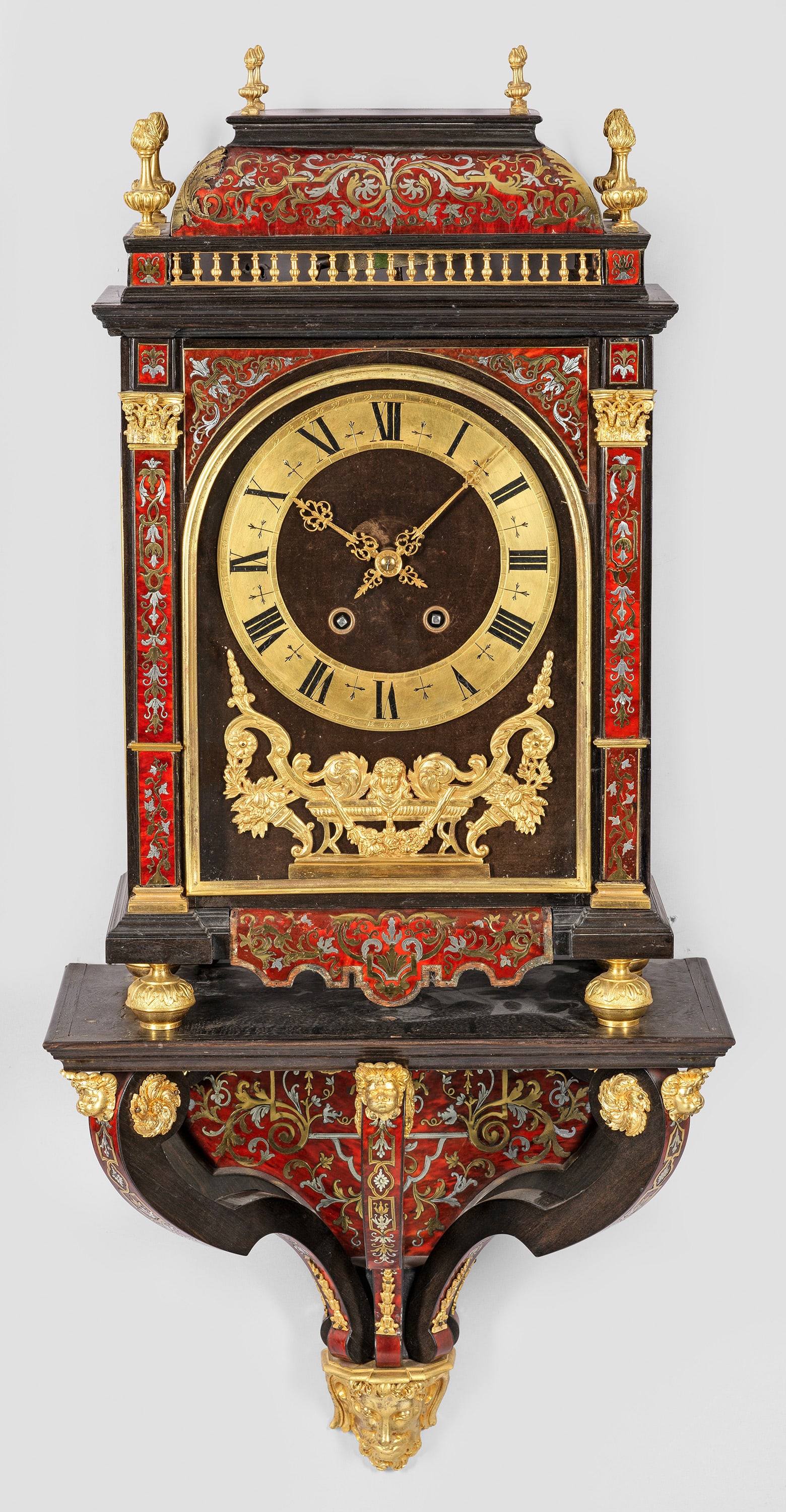 Boulle-Uhr mit Wandkonsole im Louis XIV-Stil: Holz, ebonisiert sowie Marketerie aus rot hinterlegtem Chinalack, Messing und Zinn in sog. Boulle-Technik. Hochrechteckiges, dreiseitig verglastes Uhrengehäuse, flankiert von flachen Polstern mit kor