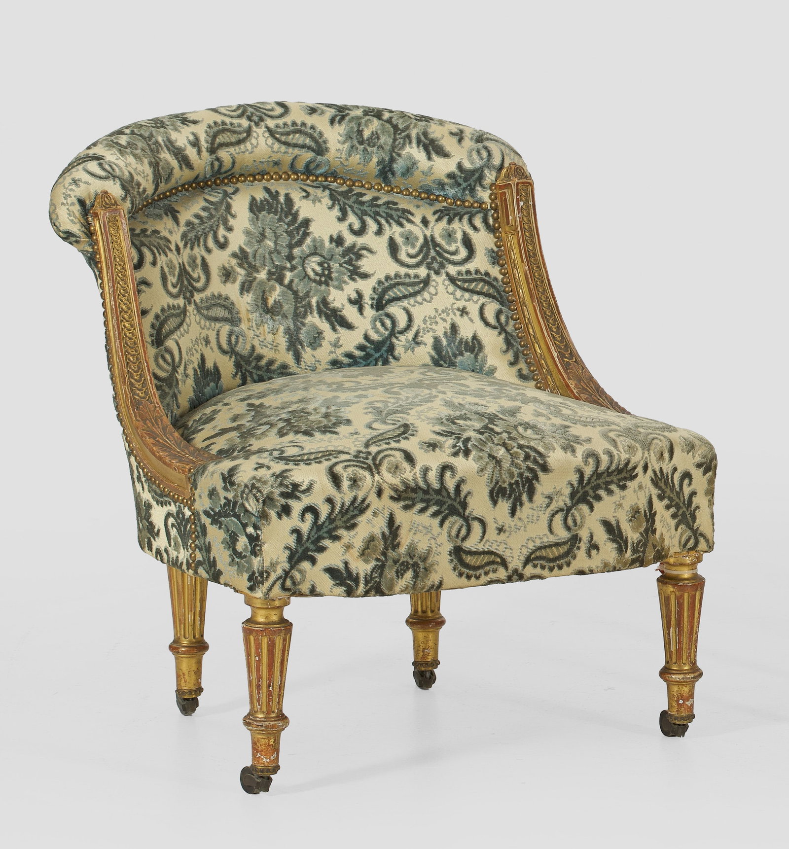Napoleon III-Hundesessel: Holz, gefasst und vergoldet. Bombierte Zarge auf kannelierten Balusterbeinen mit Rollen. Gebogte Streben mit Schuppenfries, in gebogte Rückenlehne übergehend. Allseitig gepolstert und bezogen. H. 66