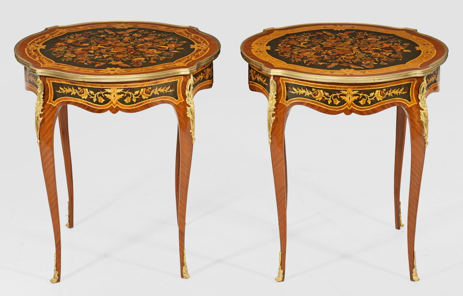 Paar Salontische im Louis XV-Stil: Mahagoni, furniert sowie Einlagen aus unterschiedlichen Hölzern. Passig geschweifte Zarge auf hohen, geschwungenen Beinen. Korrespondierende, profilgerahmte Deckplatte. Flächendeckend breit gerahmte